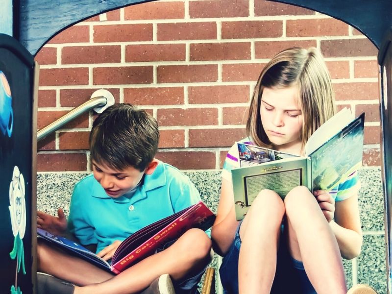 Chłopiec i dziewczynka czytają książki.